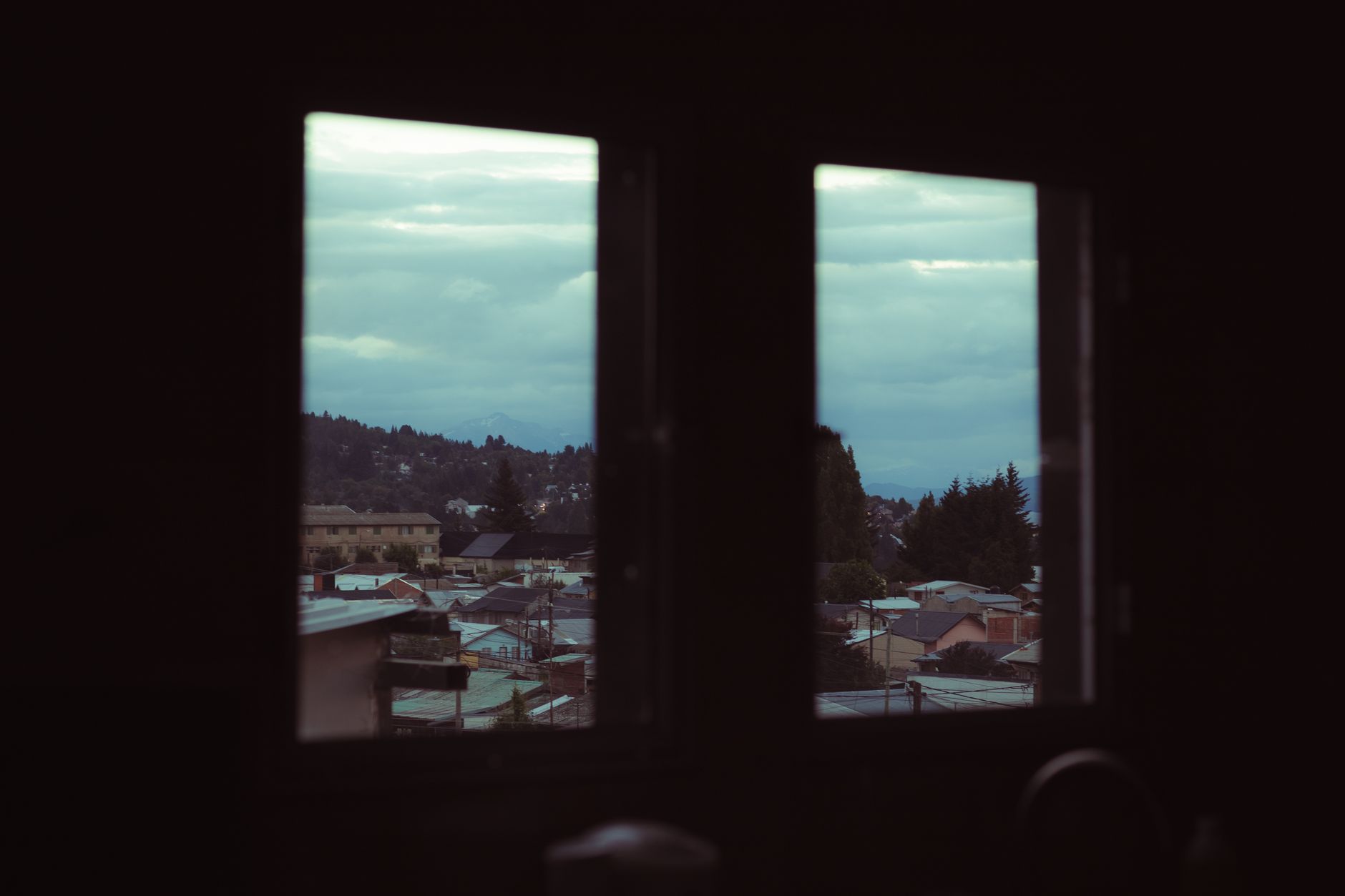 A serene view of San Carlos de Bariloche’s rooftops seen through a window on a cloudy day in San Bernardino, CA